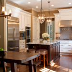 Elegant kitchen with white cabinetry and dark wood island under pendant lights.