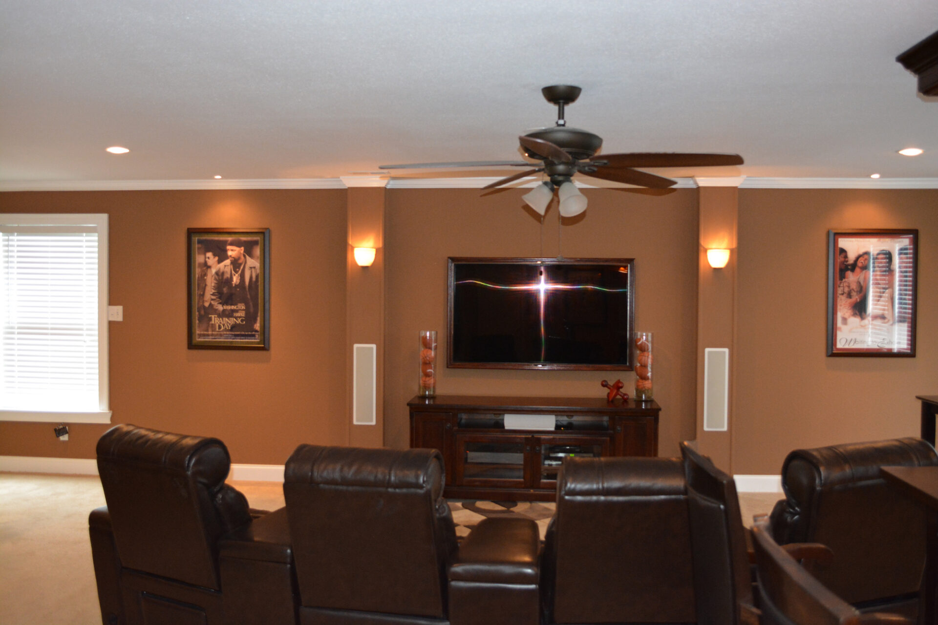Cozy living room with leather recliners, ceiling fan, and wall-mounted TV.